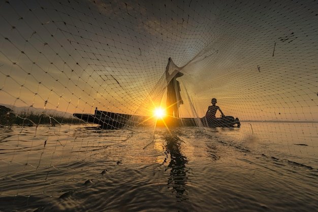 a-imagem-e-silhueta-os-pescadores-estao-saindo-para-pescar-no-inicio-da-manha-com-barcos-de-madeira-lanternas-antigas-e-redes-estilo-de-vida-do-pescador-de-conceito_39733-317